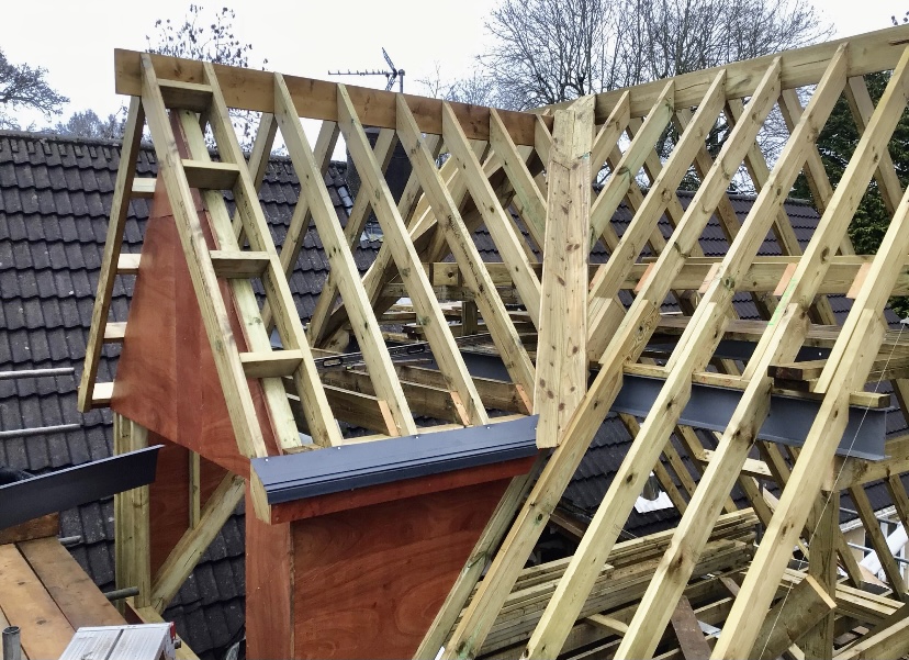 New roof trusses craned into position over an extension