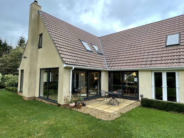 Rendered house with a rear extension, tiled roof and rooflights, seen from the lawn