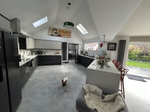 Kitchen with dark units, a rooflight and a dog bed by the island