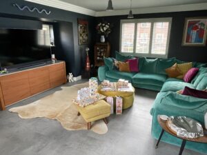 Living room with dark walls, a teal sofa and a cowhide rug