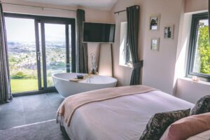 Loft bedroom with a freestanding bath and doors onto a balcony