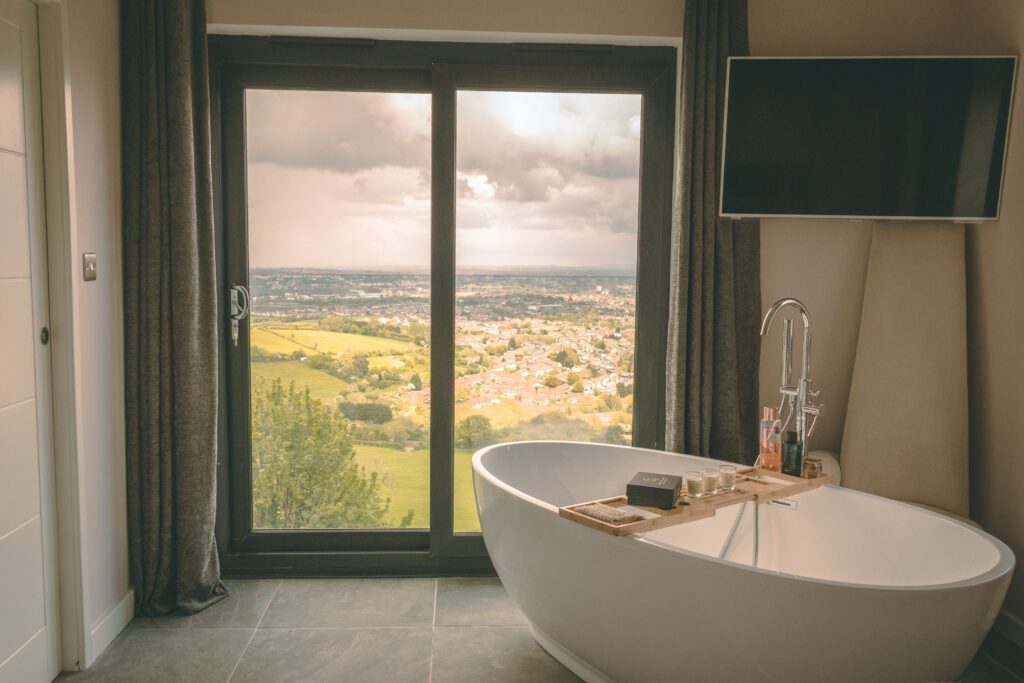 Freestanding bath beside glazed doors onto open countryside