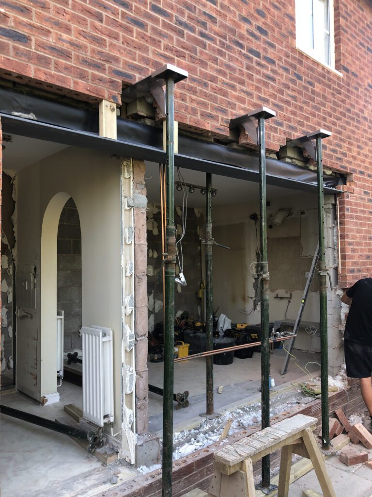 Steel goalpost frame installed to form a wide structural opening in a brick wall