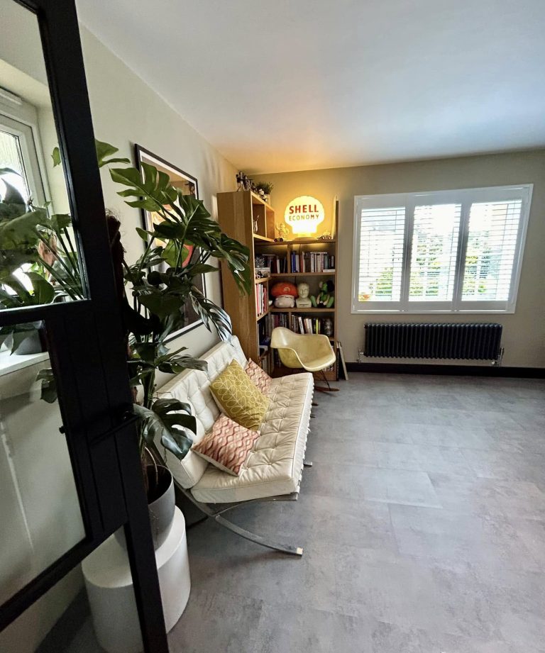 Converted garage finished as a snug and study, with plantation shutters, a column radiator and bookshelves