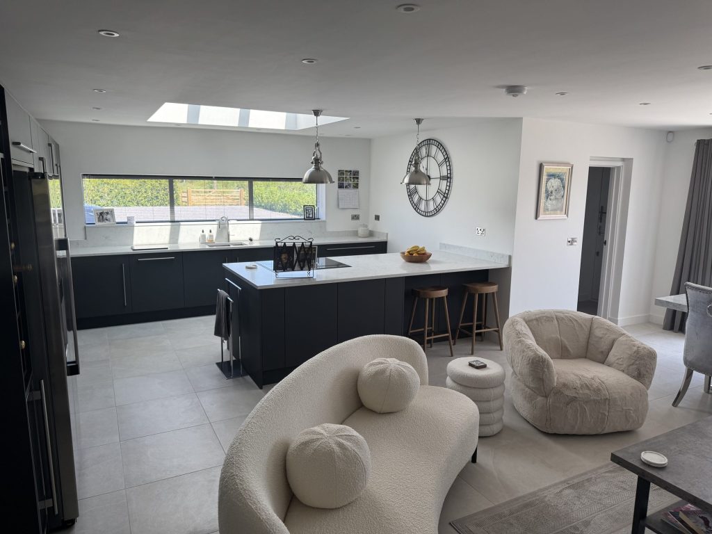 Open-plan kitchen and family room with a dark island and a wall clock