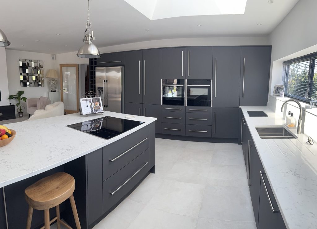 Open-plan kitchen with a dark island, integrated ovens and a rooflight