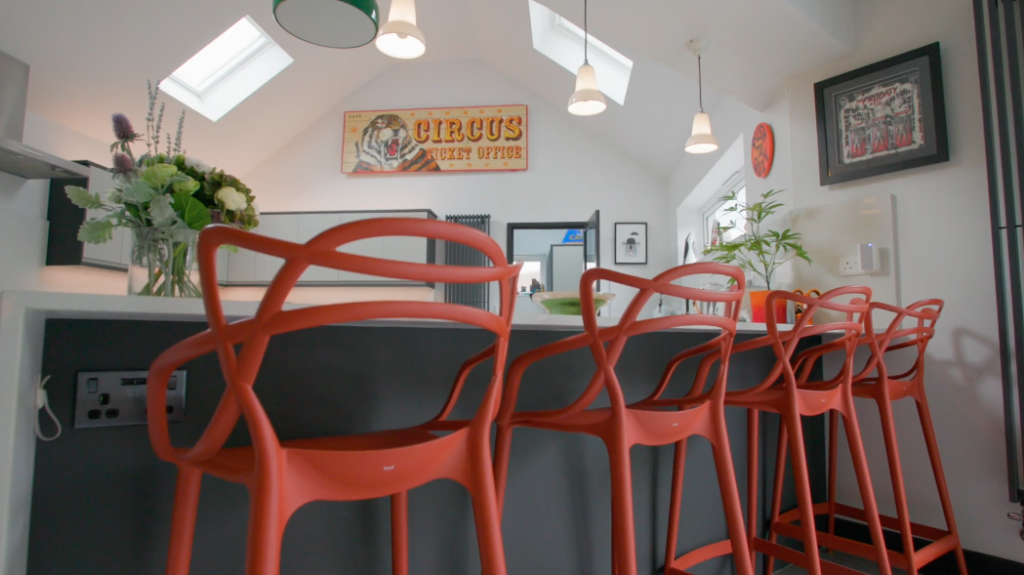 Kitchen breakfast bar with red stools beneath a rooflight