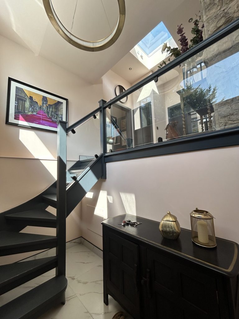 Hallway with a black spiral staircase, mirror and console table