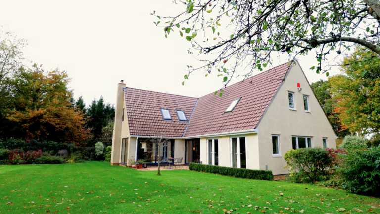 Rendered detached house with a tiled roof, seen across the rear lawn