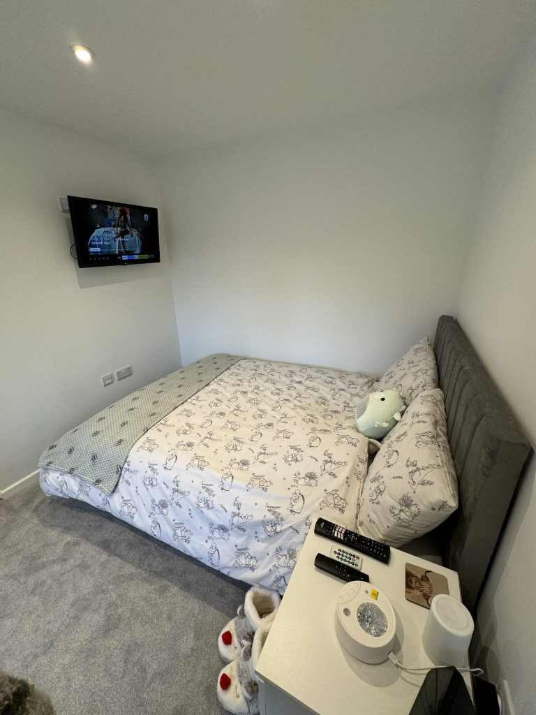 Converted garage in use as a bedroom, with a wall-mounted television