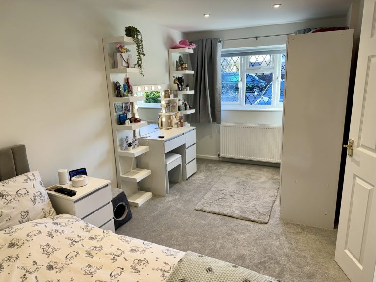 Converted garage fitted out as a bedroom with a dressing table and fitted storage