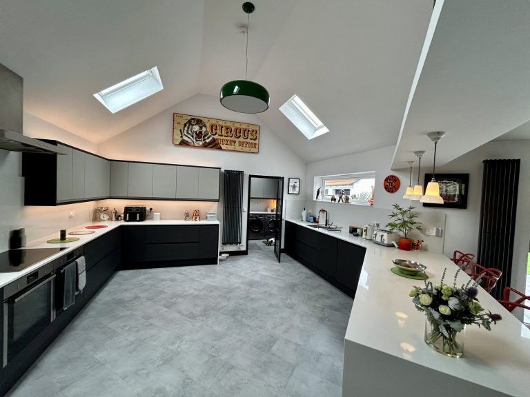 Dark green kitchen with a vaulted ceiling, rooflight and curved island