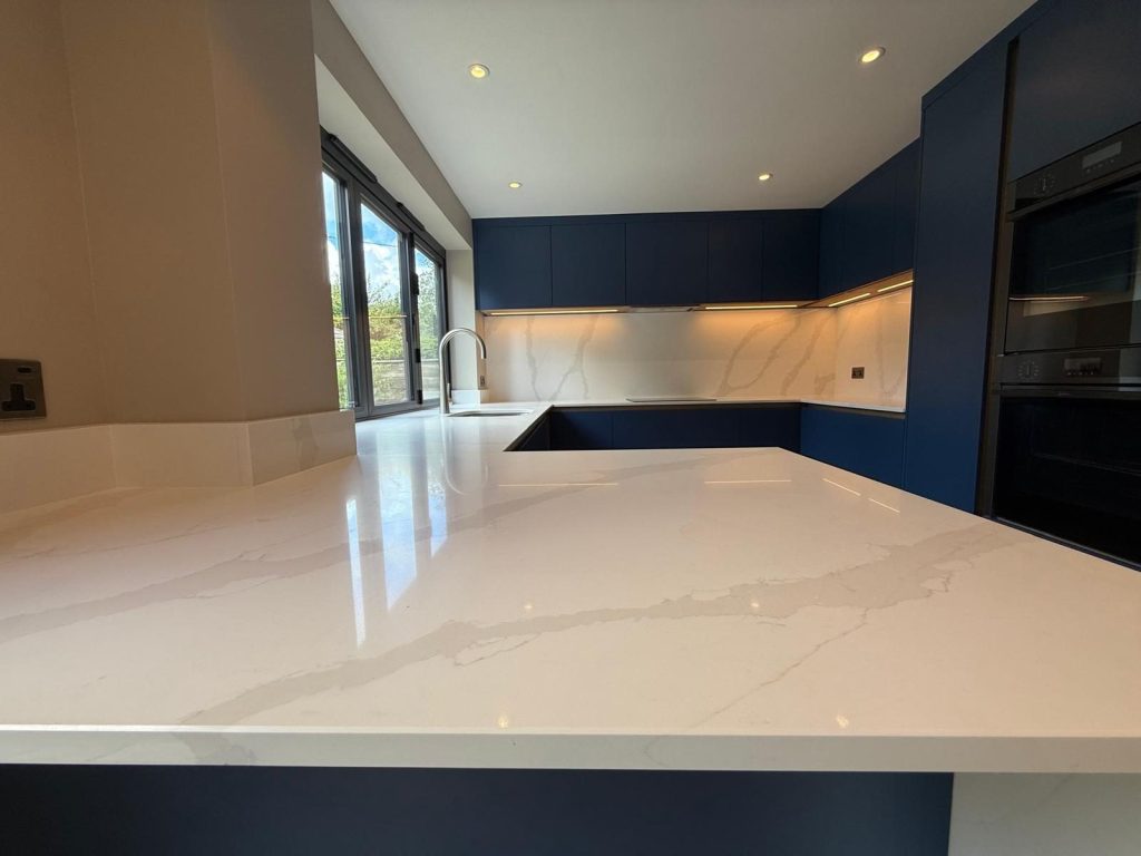 Navy kitchen with a pale worktop and full-width glazing