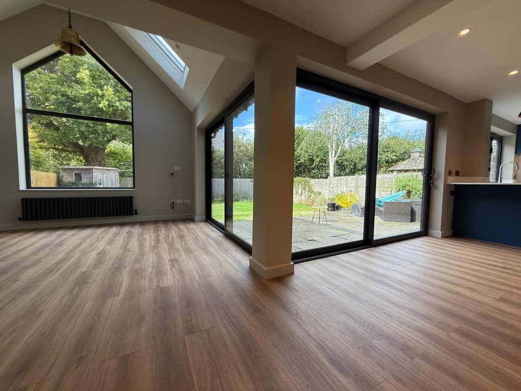 Empty extension interior with a rooflight and full-height glazing onto fields