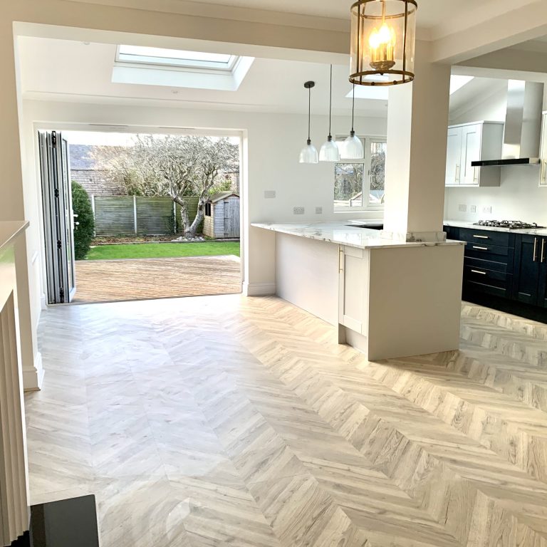 Kitchen extension with herringbone flooring, a slim island and bifold doors to the garden