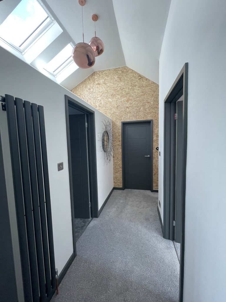 Loft landing with vertical radiators, dark doors and a rooflight above