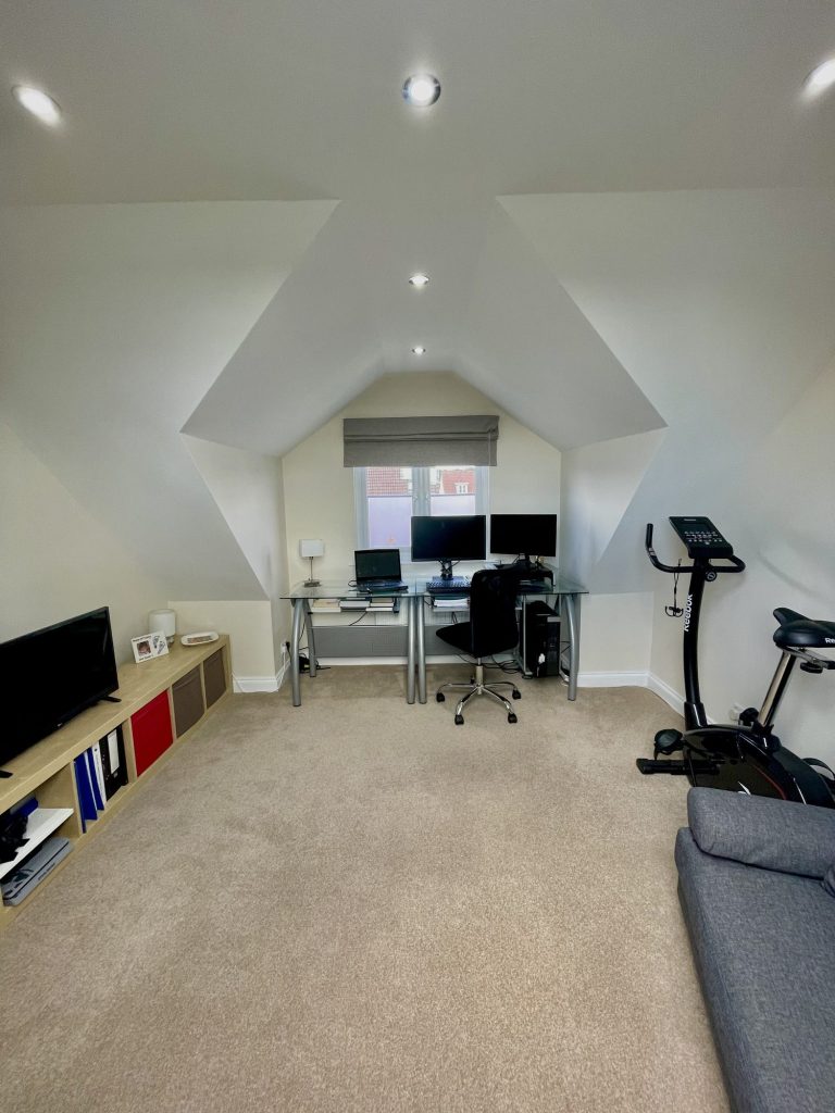 Loft converted into a home office and gym under a vaulted ceiling