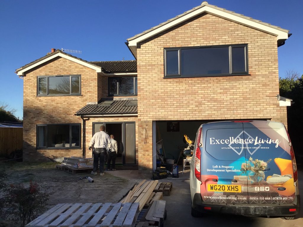 Brick house mid-renovation with a two-storey extension under way and an Excellence Living van outside