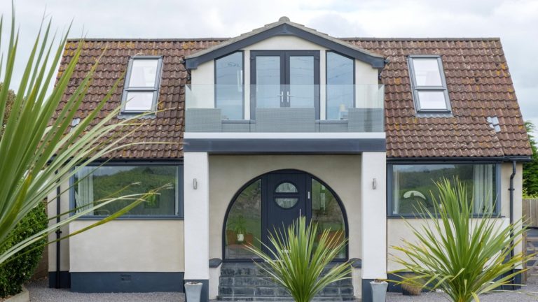 The same house after its loft conversion, with a glazed gable end, a Juliet balcony and a rooflight set into the tiled roof