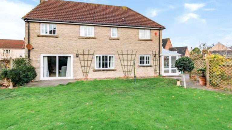 Stone-fronted house with a white sliding patio door and a plain lawn, before the extension